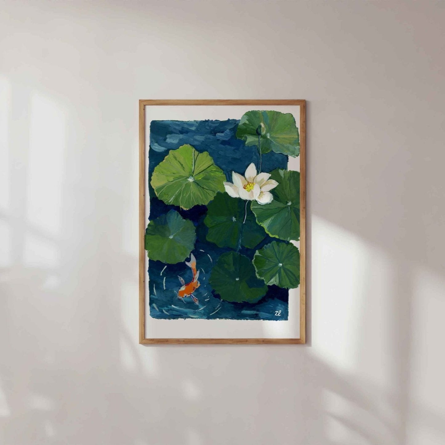 Framed artwork of a watercolor painting of a white lotus flower and green lily pads with a goldfish on a blue background.