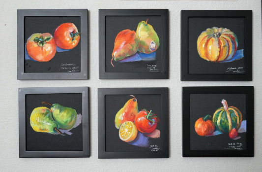 Six framed paintings of fruits and vegetables on a wall.