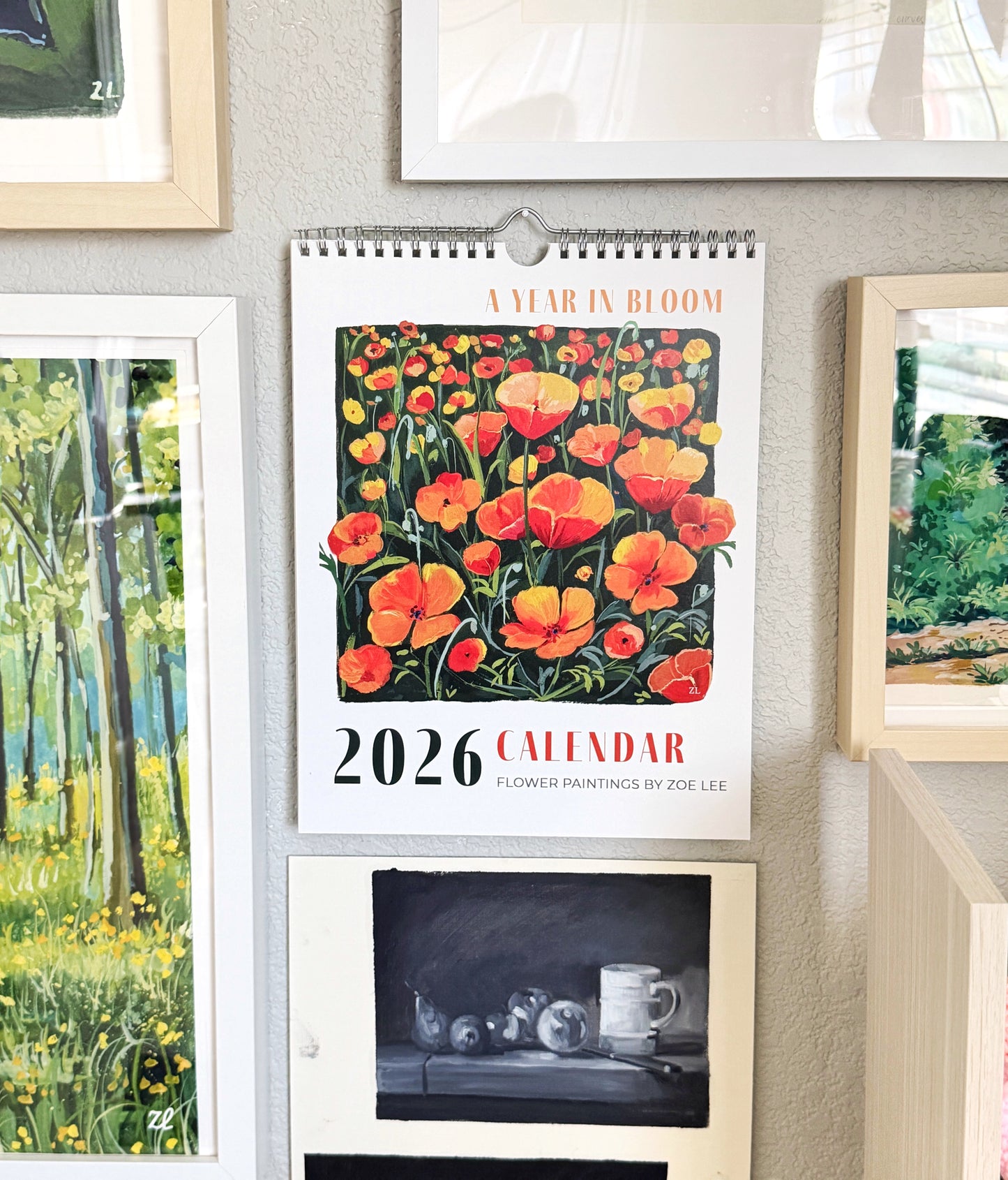 2026 calendar with floral design hanging on a wall with framed pictures.