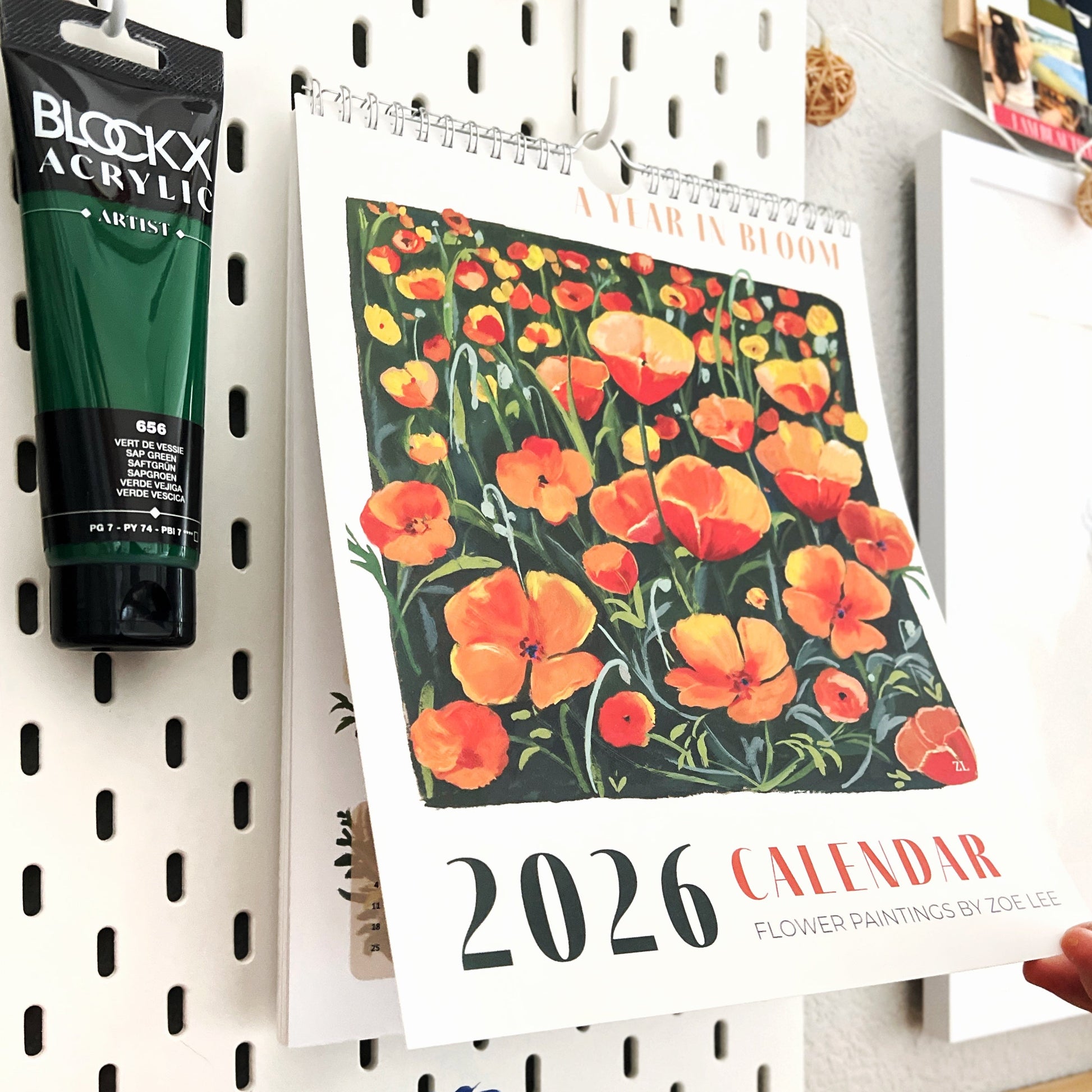 2026 calendar with floral design on a pegboard wall with art supplies.