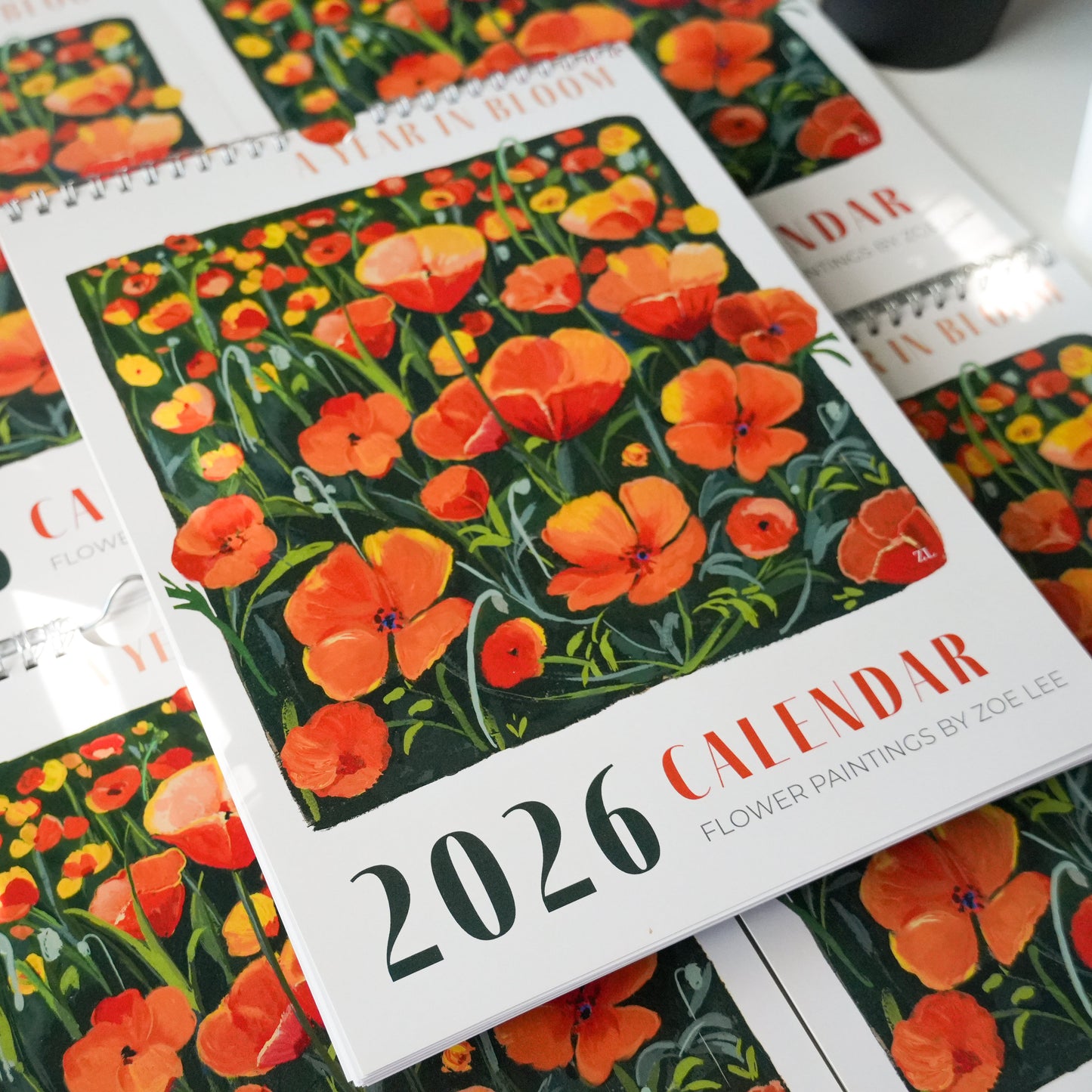 Floral 2026 calendar on a white surface with a small plant.