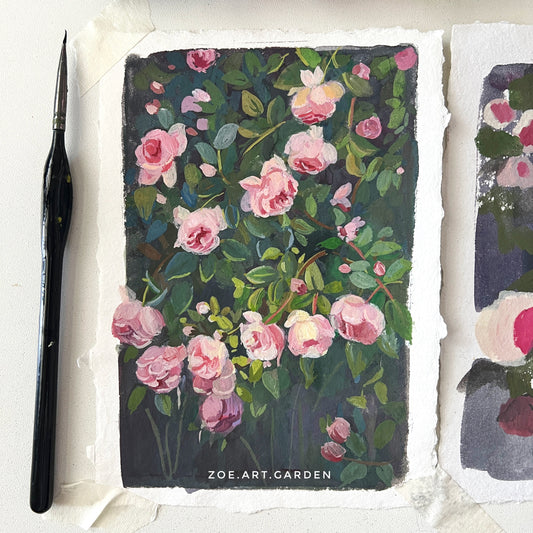 Floral painting with pink flowers on dark background, watercolor set, and brush in the background.
