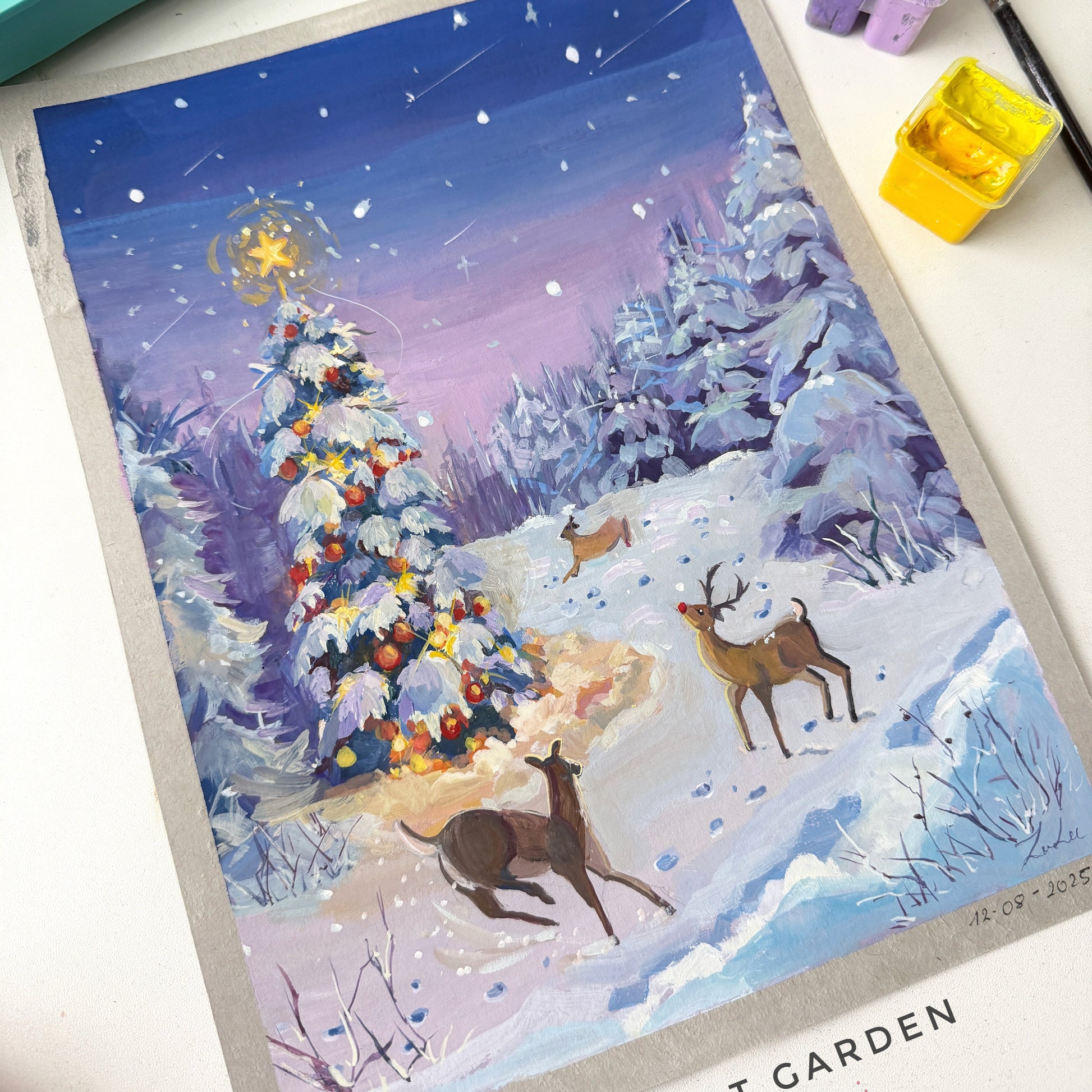 Winter scene with a decorated tree and deer, surrounded by art supplies.