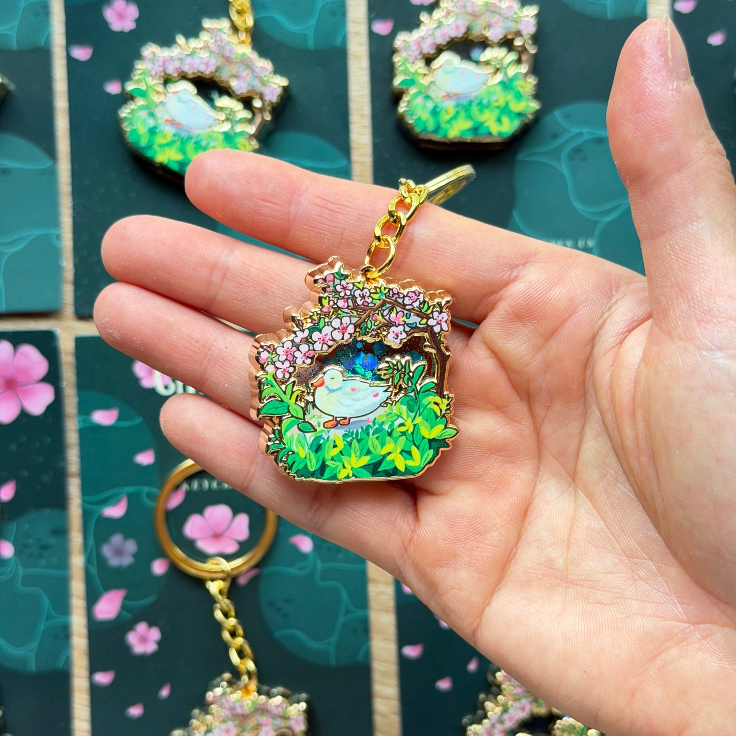 Hand holding a colorful brooch with more brooches on a patterned background