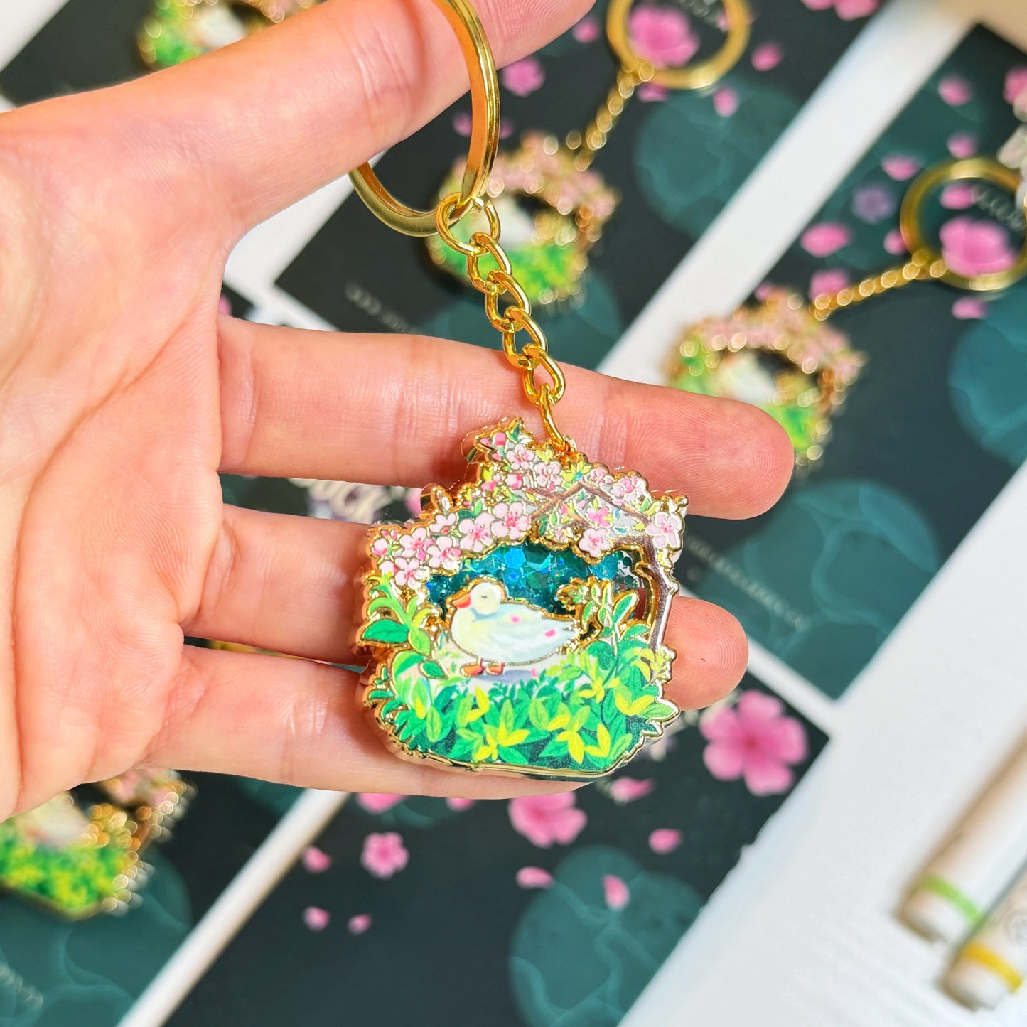 Hand holding a colorful keychain with floral design against a patterned background