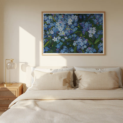 A framed floral wall art print featuring blue and white flowers with green leaves, hung above a neatly made bed with beige bedding in a softly lit bedroom.
