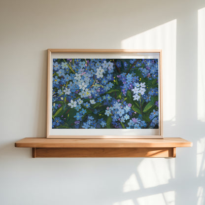 A framed floral painting of blue forget-me-nots with green leaves, displayed on a light wood floating shelf against a warm off-white wall with soft window shadows.