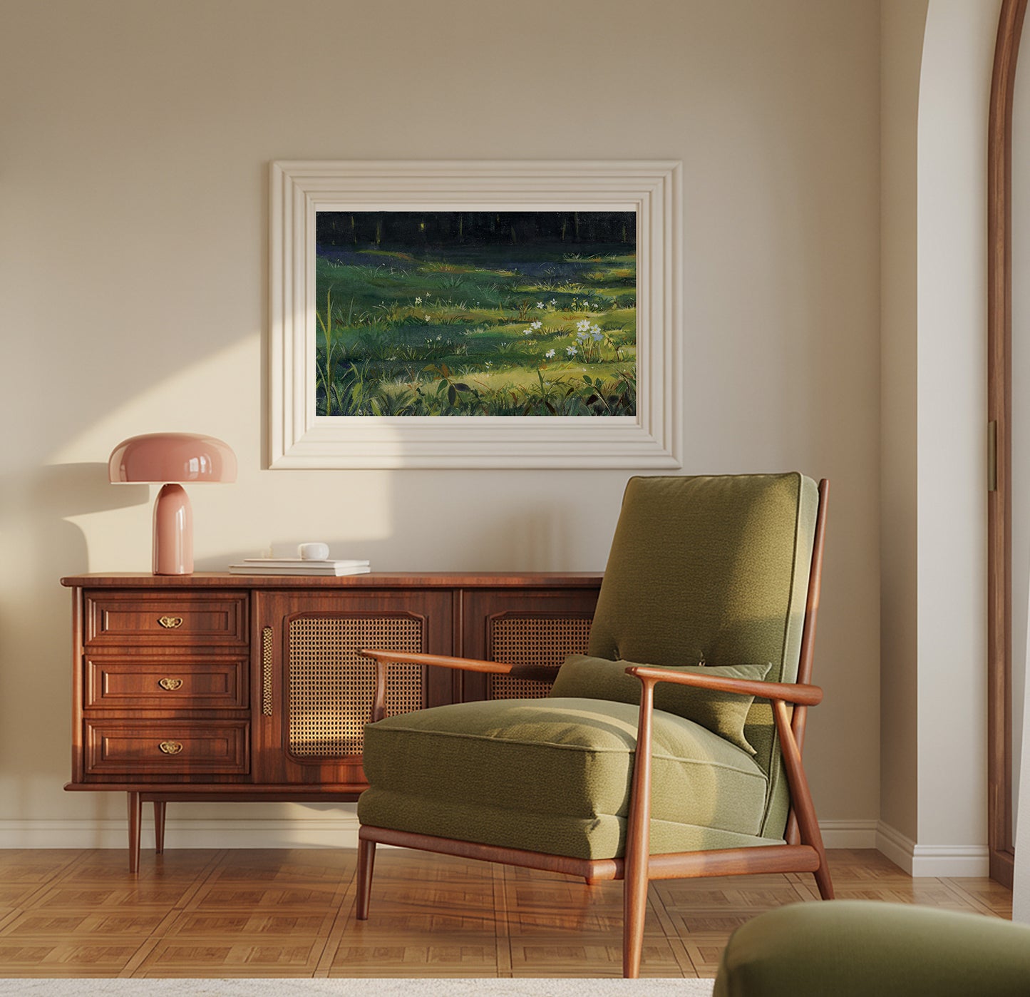 A framed landscape painting of a green field under a dark sky hangs on a beige wall above a mid-century modern wooden credenza and olive green armchair.