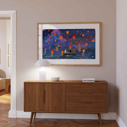 Framed artwork of floating lanterns above a wooden sideboard in a room.