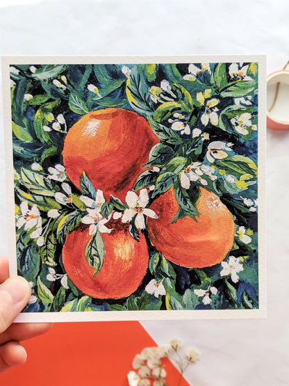 Framed artwork of oranges and flowers on a white background