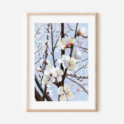 Framed artwork of cherry blossoms against a light blue sky on a white wall.