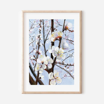 Framed artwork of cherry blossoms against a light blue sky on a white wall.