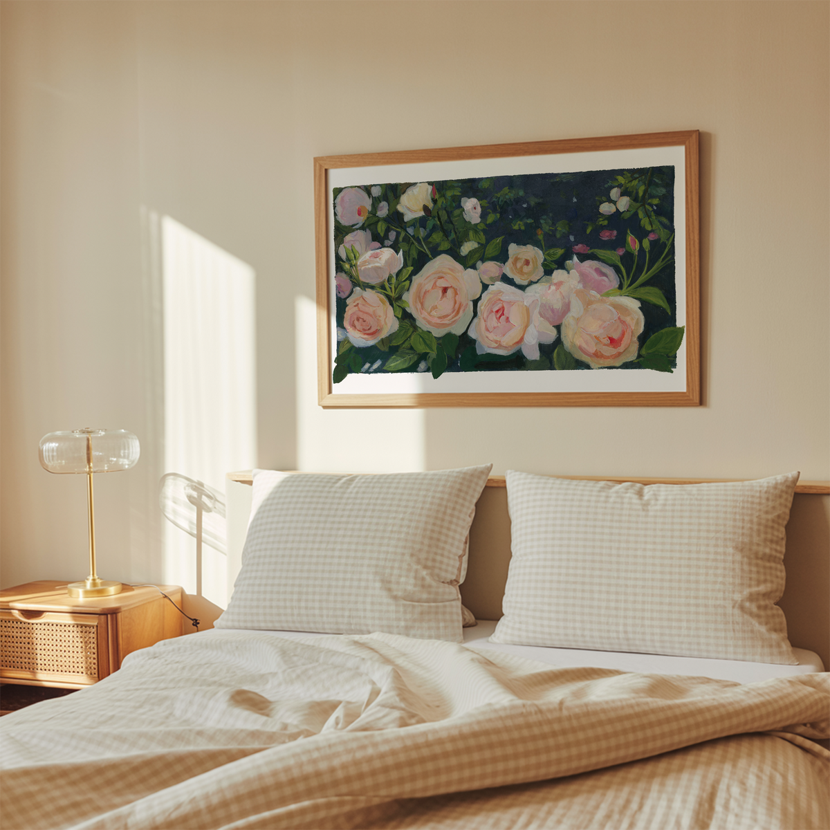 A framed floral art print hangs on a beige wall above a neatly made bed with cream gingham bedding and two pillows in a softly lit bedroom.